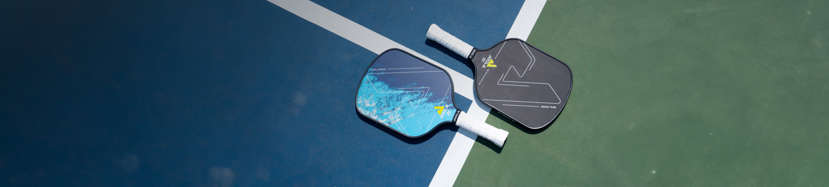 Banner image of two JOOLA Solaire Pickleball Paddles laying on a court opposite ways.